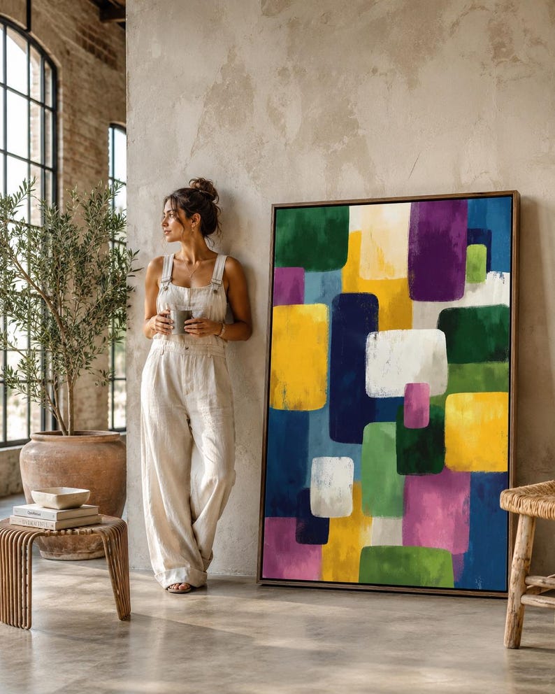 A framed geometric abstract artwork features overlapping colourful blocks—green, yellow, purple, blue and white—arranged in an irregular, layered