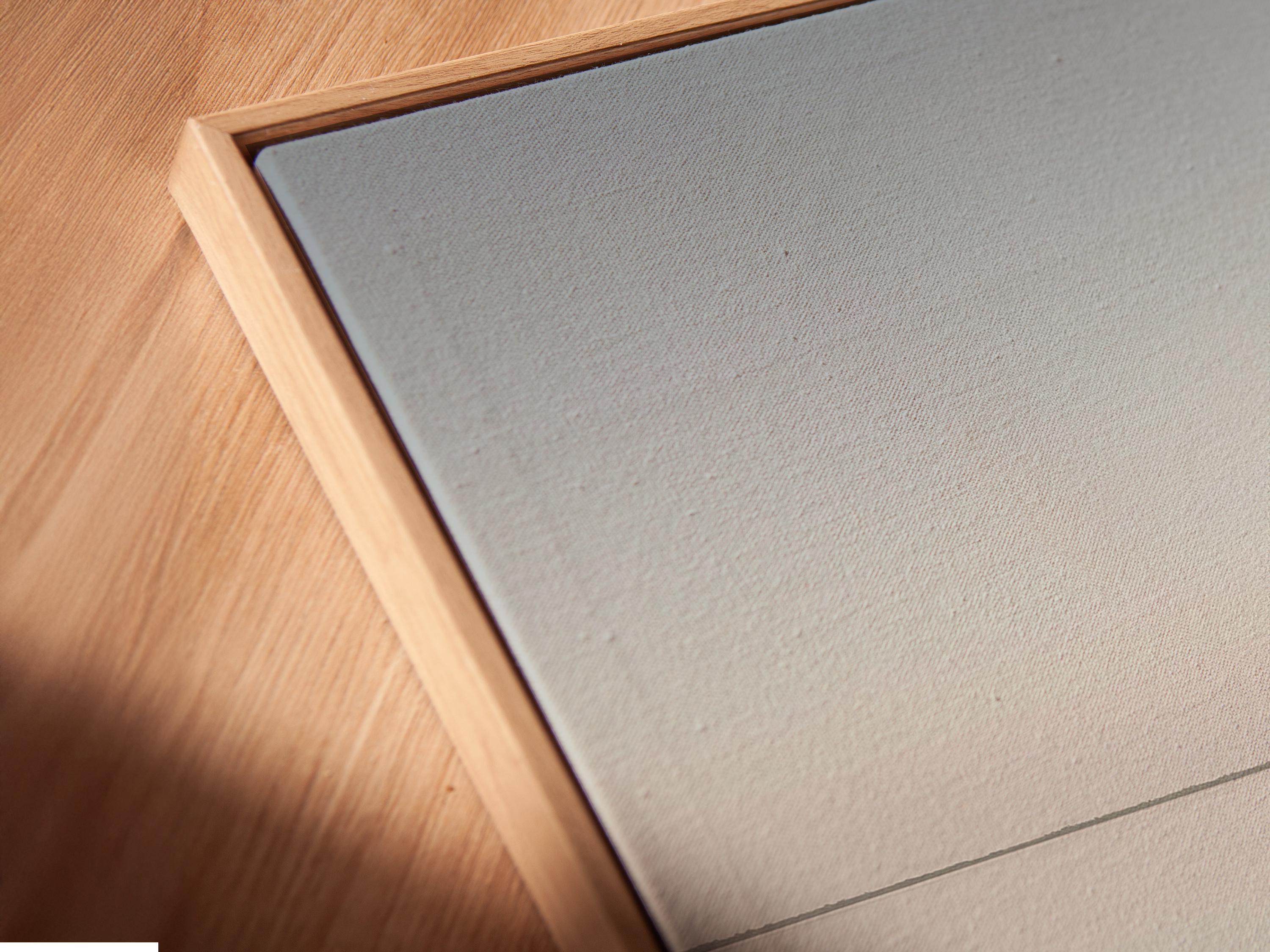Neutral sailboat seascape with a pale sail on calm water and a hazy horizon detail view