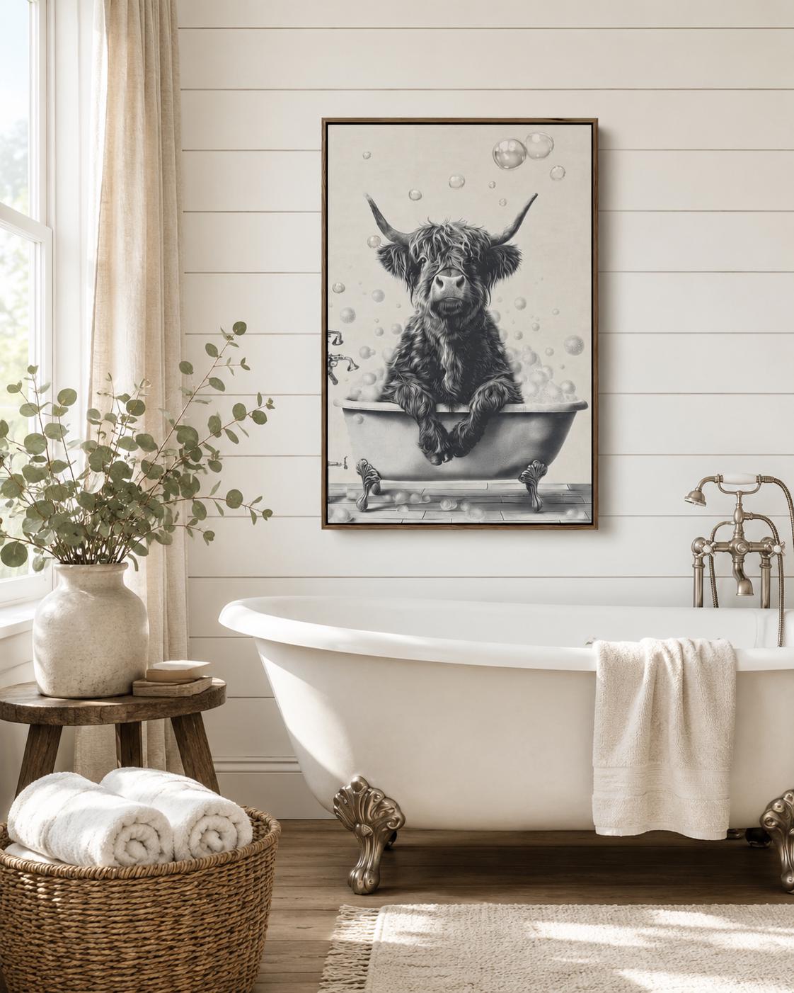 Woman holding a mug standing beside a framed monochrome highland cow bathtub artwork