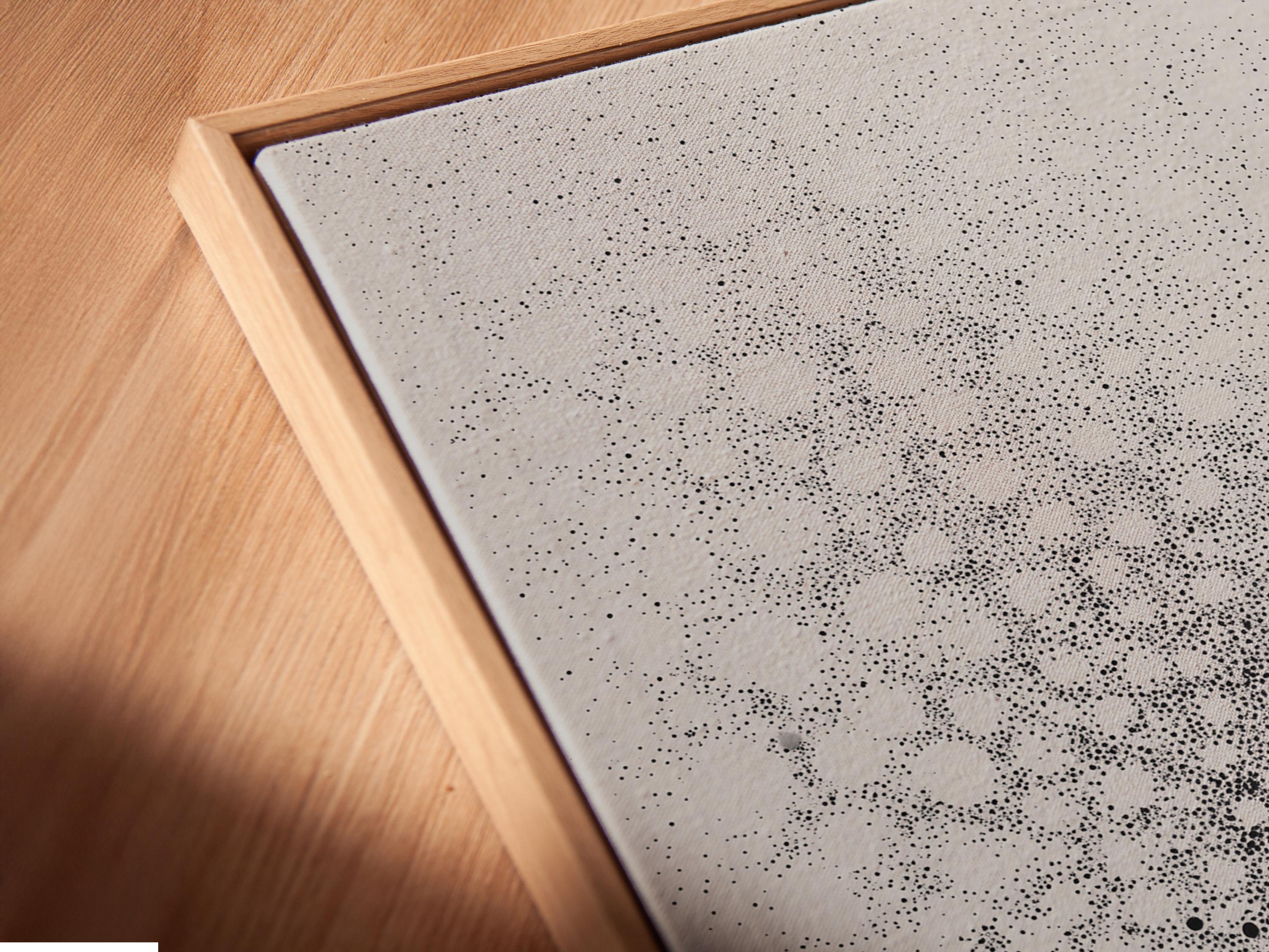 Monochrome abstract artwork with speckled dot clusters and an elongated figure silhouette detail view