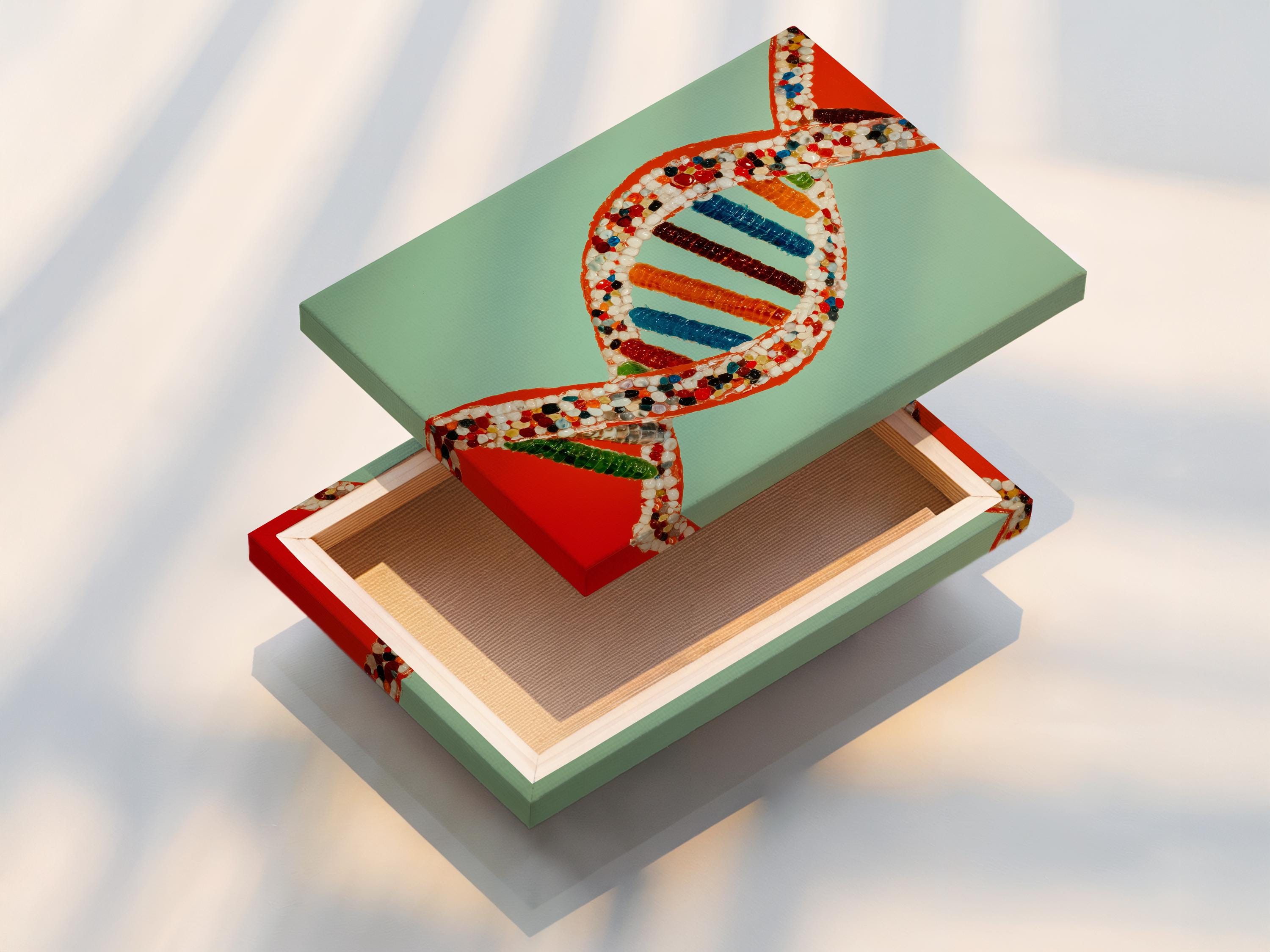A researcher in a white lab coat stands next to a framed DNA double helix artwork