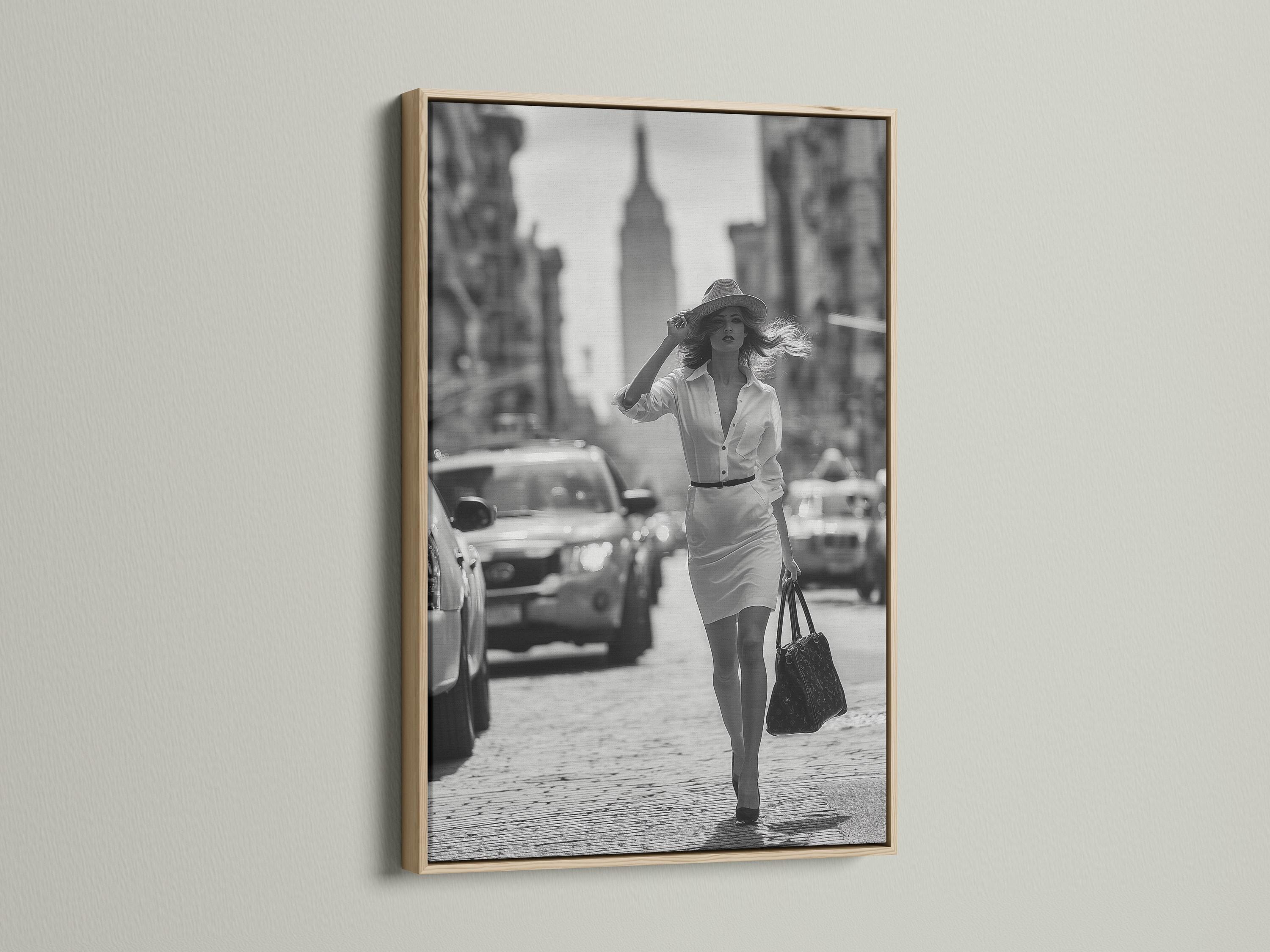 A black-and-white street photograph shows a stylish woman walking forward with a hat and handbag, with blurred city buildings and cars behind her