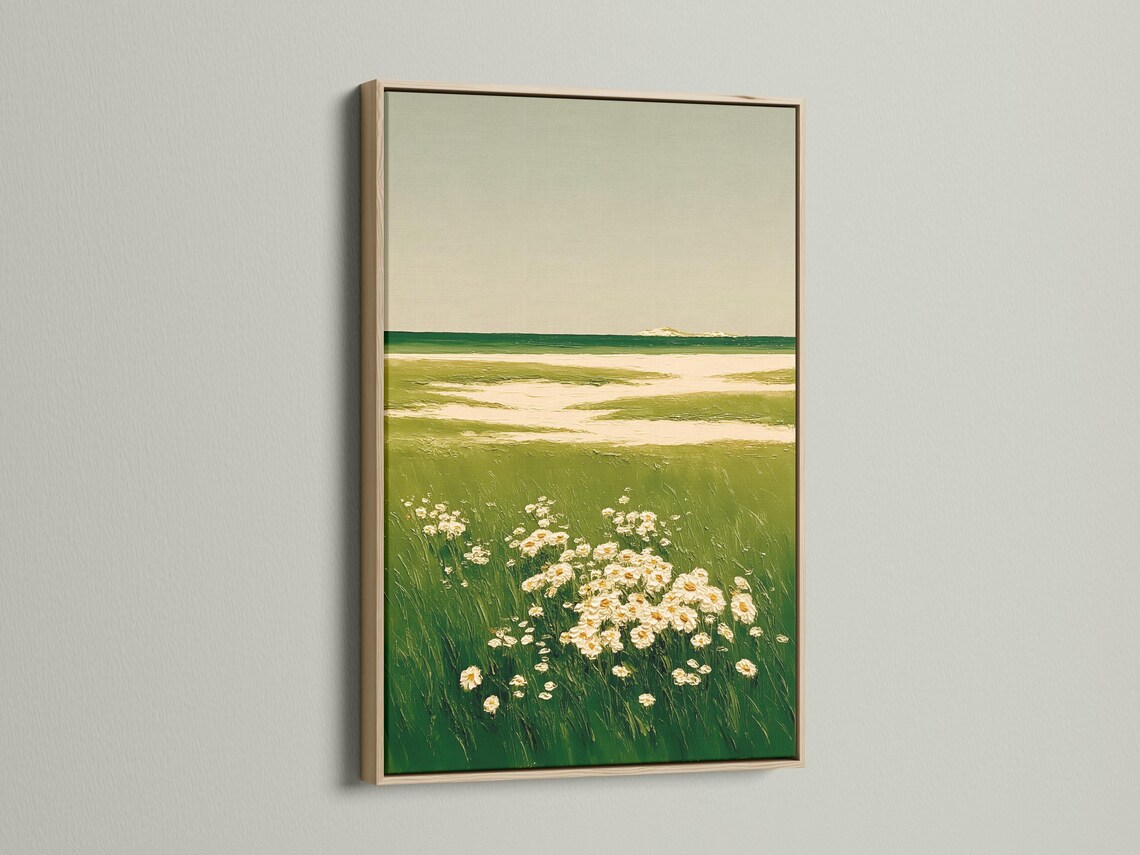 A framed landscape artwork on a light background wall showing green meadow grasses and cream flowers
