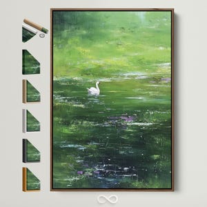 May include: An abstract landscape painting featuring a white swan on a green lake. The artwork is framed in a dark brown wooden frame. The painting has a textured, impressionistic style with shades of green and white.