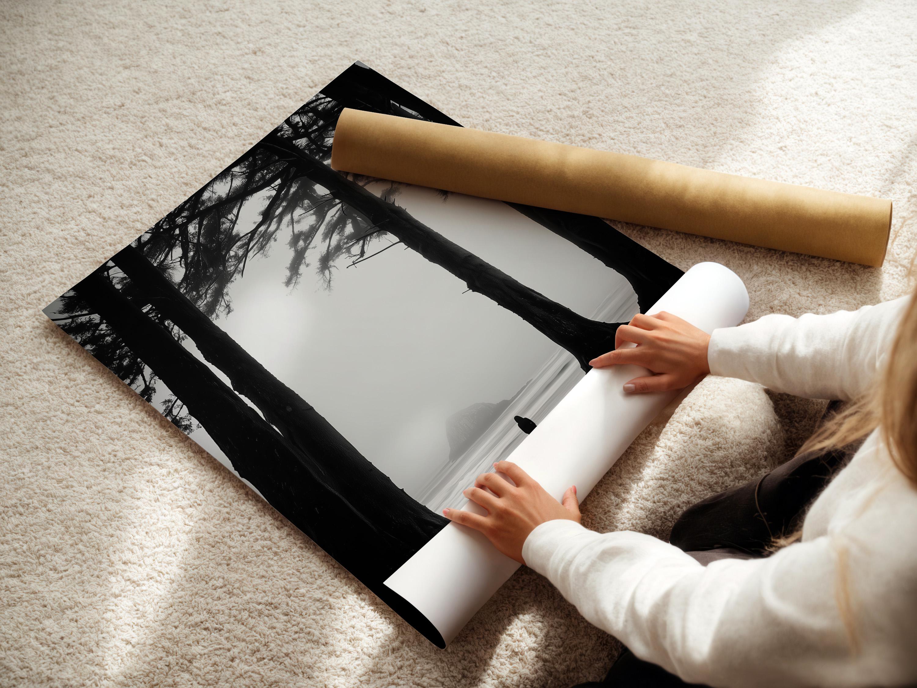 Monochrome seascape with dark tree trunks framing a foggy beach and a small lone figure detail view