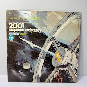 May include: Vintage vinyl record album cover for "2001: A Space Odyssey." The artwork features a spaceship, space station, and planets against a dark blue and black background. The album title and production details are prominently displayed.