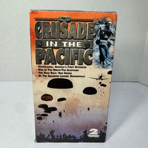 Könnte beinhalten: Eine DVD-Hülle mit dem Titel "Crusade in the Pacific" mit Bildern von Soldaten, Flugzeugen und Fallschirmen. Die Hülle ist orange und braun mit dem Text "Guadalcanal: America's First Offensive" und "2 Videos."