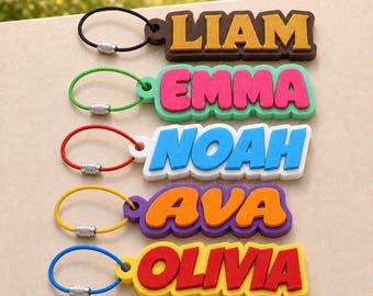 May include: Five custom keychains featuring the names LIAM, EMMA, NOAH, AVA, and OLIVIA in bold, raised letters. Each keychain has a colorful, flexible wire loop with a metal screw-top fastener, showcasing distinct color combinations for each name.