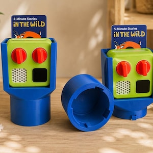 May include: Two blue plastic holders each containing a lime green electronic device with two red knobs, a white speaker mesh, and a black square. Each device displays a card labeled 5-Minute Stories IN THE WILD. A blue cylindrical cap sits between them.