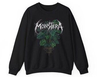 May include: Black sweatshirt featuring a graphic of a Monstera plant in a decorative pot. The word "MONSTERA" is printed above the plant in a stylized, white font. The sweatshirt has a crew neck and long sleeves.