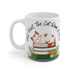 Puede incluir: Taza de cerámica blanca con una ilustración de un gato durmiendo sobre una pila de libros. El gato es blanco con marcas marrones. La taza tiene el texto "Plot Twist, The Cat Read It First" en escritura negra.