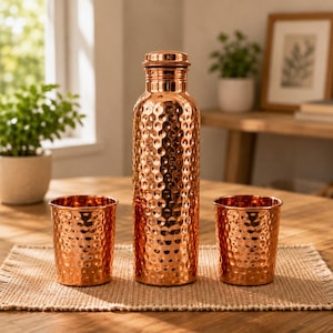 May include: A tall, cylindrical copper water bottle with a hammered texture and a matching screw-top lid, flanked by two smaller, matching hammered copper tumblers. The set features a polished, reflective metallic finish throughout all pieces.