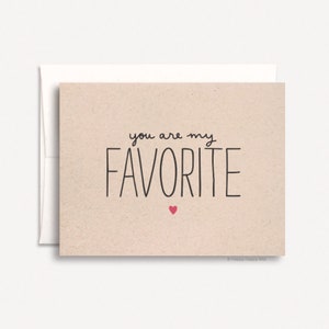 May include: A card with a beige background and black text that reads "you are my favorite" with a small red heart below the text. The card is signed "Happy Daffy Bits".