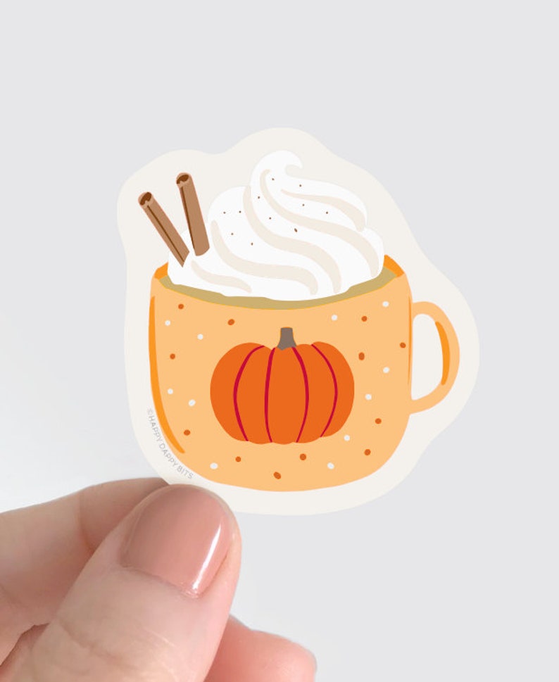 May include: A sticker of a pumpkin spice latte in a mug with whipped cream and cinnamon sticks. The mug has a white background with orange polka dots and a small pumpkin on the front. The text "Happy Daffy Bits" is on the bottom of the mug.