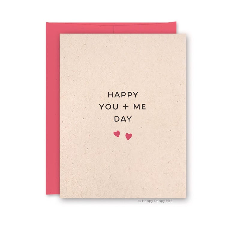 May include: A greeting card with a pink envelope. The card is beige with the words "HAPPY YOU + ME DAY" in black. Two small pink hearts are below the text. The bottom right corner has the text "Happy Dappy Bits".