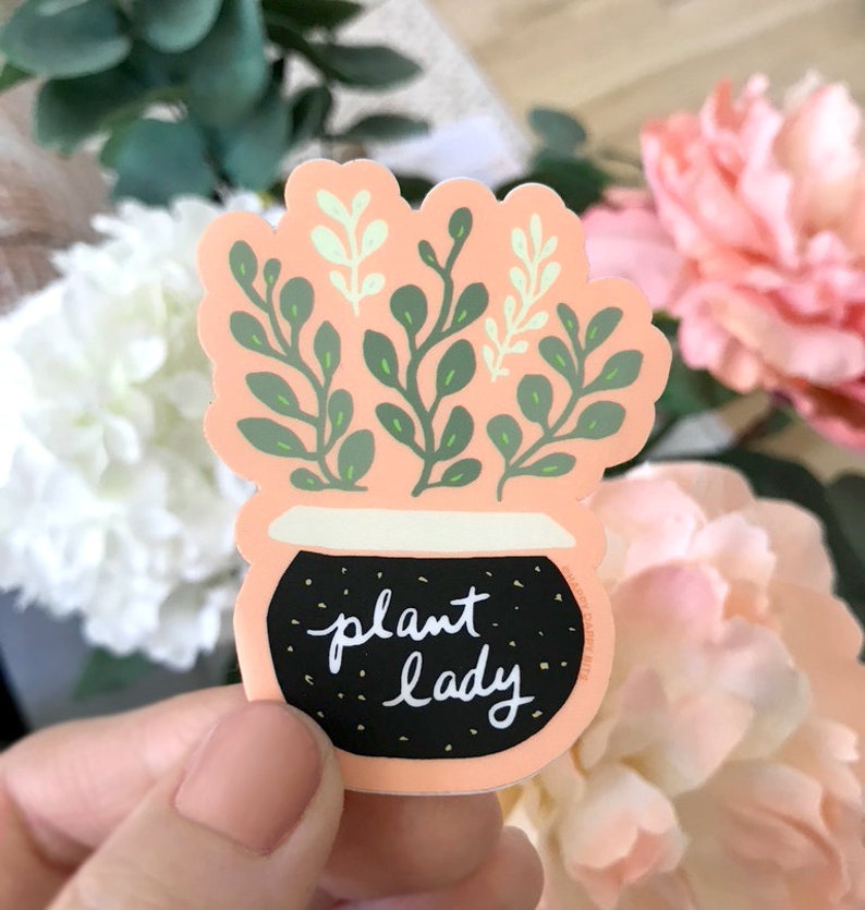 May include: A peach-coloured sticker with a black pot and green plant. The pot has white speckles and the text "plant lady" in white.