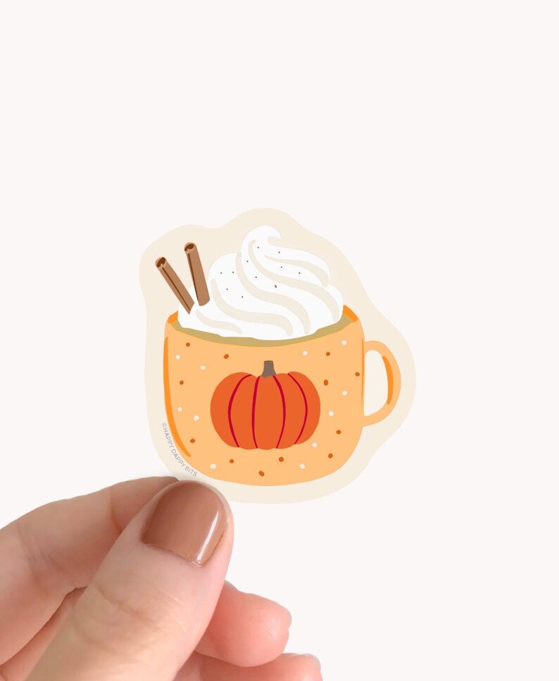 May include: A sticker of a pumpkin spice latte in a mug with a pumpkin on the front and whipped cream on top. The mug is orange with white polka dots. There are two cinnamon sticks sticking out of the whipped cream.