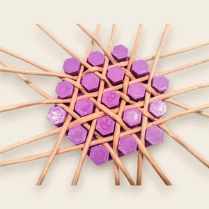 May include: A woven circular design featuring purple hexagonal pieces with numbers, intertwined with light brown wooden sticks. The design is centered, with the wooden sticks radiating outwards, creating a starburst effect. The numbers on the purple pieces are visible.