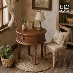 Op de afbeelding: Miniatuur poppenhuismeubelset. Een ronde, donkerbruine tafel met een lade, een kleine lamp, een ingelijste foto en een stoel met een bloemenkussen. Een kleine plant in een geweven mand staat op de grond. De schaal is 1:12.