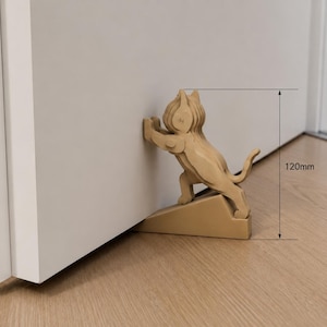 May include: A light brown cat-shaped doorstop made of layered material, positioned to hold a white door open. The cat figure is depicted pushing against the door surface. A technical diagram indicates a total height measurement of 120mm.