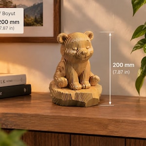 Pode incluir: Uma estatueta de urso impressa em 3D de cor castanho-claro, composta por camadas sobrepostas e assente numa base texturada. O urso tem um aspeto canelado e mede 200 mm de altura. A figura tem olhos fechados e um nariz pequeno e arredondado.