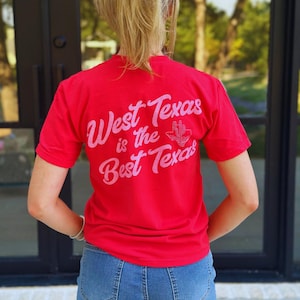 May include: A red t-shirt with the text "West Texas is the Best Texas" in a cursive font and a cactus graphic. The shirt is paired with blue denim shorts. The image is taken from behind.