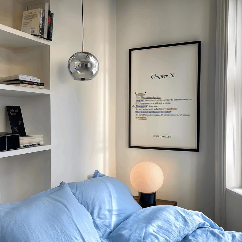 May include: A bedroom scene featuring a light blue bedspread and pillows. A framed print with the text "Chapter 26" hangs on the wall. A spherical lamp sits on a nightstand, and a chrome pendant light hangs from the ceiling.