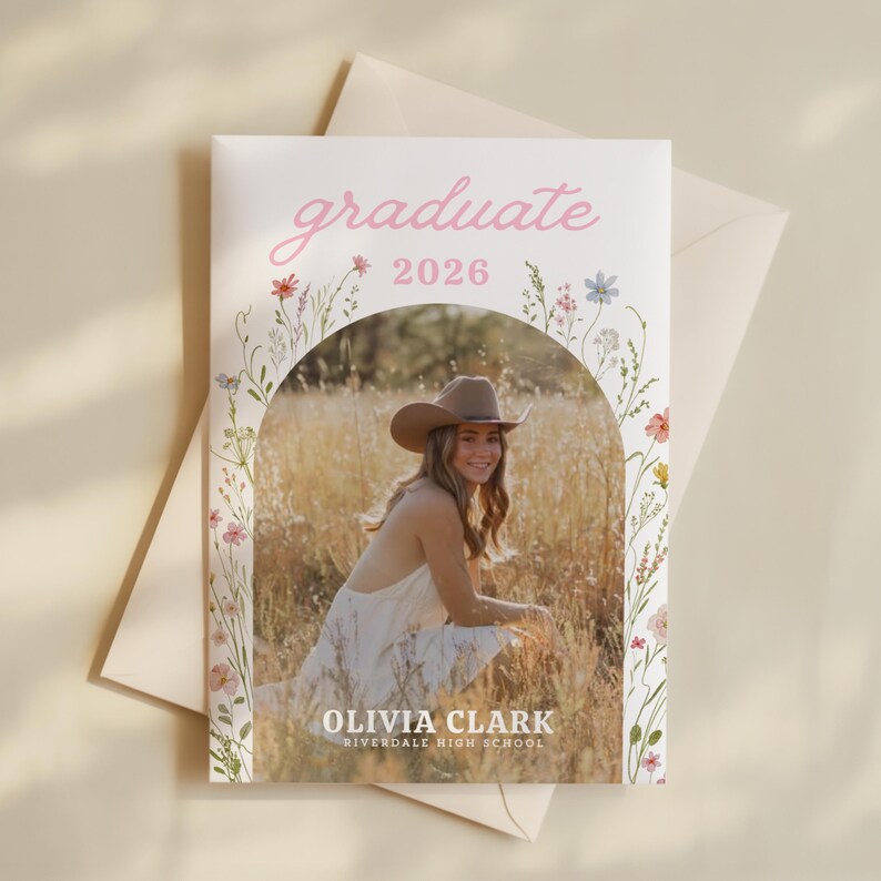 Puede incluir: Una tarjeta de anuncio de graduaci&oacute;n con la palabra "graduate" en escritura rosa sobre el a&ntilde;o "2026". La tarjeta presenta una foto de una persona con sombrero de vaquero, con el nombre "Olivia Clark" y "Riverdale High School" debajo. Acentos florales enmarcan la foto.