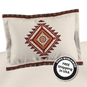 May include: Cream-colored pillowcase with a geometric design in shades of red, orange, and brown. The central pattern is a diamond shape with a sunburst-like center. The border features a repeating pattern.
