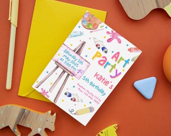 Può includere: Un invito a una festa d'arte con testo colorato e illustrazioni di materiali artistici. L'invito include il testo "Art Party" e "5th Birthday di Katie". Una busta gialla e giocattoli di legno su una superficie arancione.