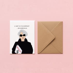 May include: A greeting card with an illustration of a woman wearing sunglasses and a black outfit, holding a magazine. The card reads "A card? On your birthday? ...groundbreaking." A brown envelope is next to the card on a pink background.