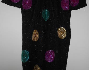 May include: A black sequined dress with colorful circles. The circles are made of sequins and are in shades of gold, teal, pink, and purple.