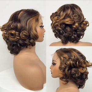 Puede incluir: Una peluca rizada marrón y rubia con una parte delantera de encaje. La peluca está peinada con un corte corto, tipo bob, con rizos voluminosos. El cabello tiene reflejos rubios más claros en todo el color base marrón. La peluca se muestra en una cabeza de maniquí.