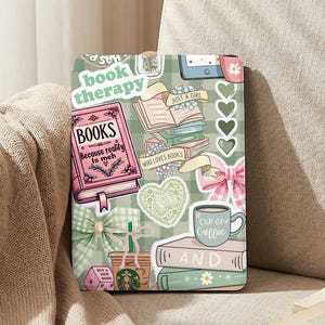 Könnte beinhalten: Eine Tablet-Hülle mit Aufklebern und Illustrationen zum Thema Bücher. Das Design umfasst ein rosa Buch mit dem Text "BOOKS Because reality is meh", eine Kaffeetasse und die Worte "book therapy". Der Hintergrund ist ein grün-weiß kariertes Muster.