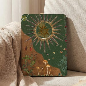 May include: A decorative tablet case featuring a whimsical design. The case has a green background with a large sunburst, mushrooms, and playful frog illustrations. Butterflies and other small details add to the artistic flair.