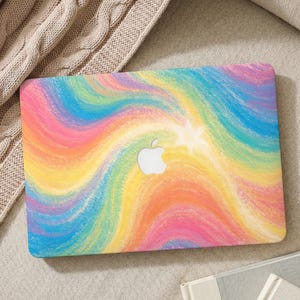 May include: A colorful laptop case with a rainbow swirl design. The case features a vibrant mix of pink, yellow, orange, and blue hues, with a white Apple logo in the center. The case is rectangular and appears to be made of a hard, protective material.
