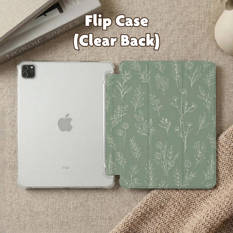 May include: A tablet flip case with a clear back and a sage green front cover featuring a white line-art botanical pattern of various wildflowers and leaves. The text Flip Case (Clear Back) is visible above the device, which has a camera lens.