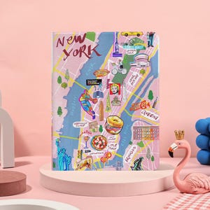 May include: A pink New York City map design on a notebook cover. The cover features illustrations of landmarks, food, and the text "New York". The map includes the Hudson and East Rivers, and the boroughs of Brooklyn and Queens.