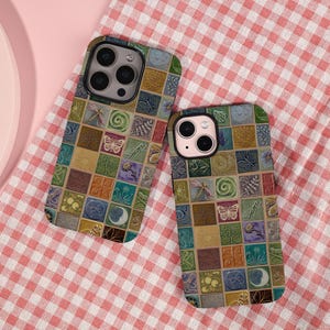 May include: Two phone cases with a colorful mosaic tile design. The cases feature a variety of square tiles with images of butterflies, dragonflies, and flowers. The cases are on a red and white checkered surface.
