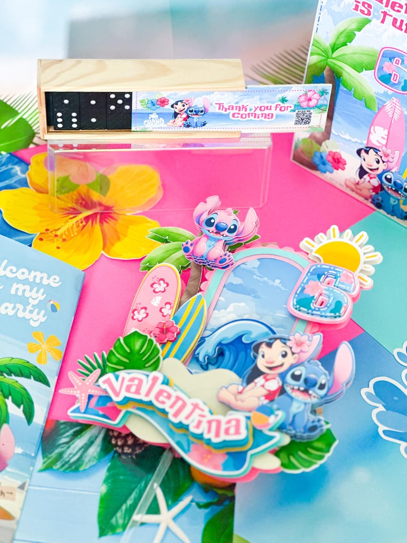 May include: A colourful party scene with a wooden domino set, character cutouts, and decorative elements. The scene includes a pink background, tropical flowers, and the name "Valentina" in a decorative sign. The theme appears to be a tropical or Hawaiian-themed party.