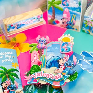 May include: A vibrant birthday party display with Lilo & Stitch decorations. The focal point is a cake topper with the name "Valentina" and the number 6. Party bags and a wooden box with text are also present.