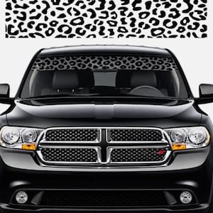May include: A black SUV featuring a windshield sun visor strip with a black and white leopard print pattern. The vehicle has a prominent chrome-trimmed grille, dual headlights, and fog lights. The leopard print design is also shown separately above.