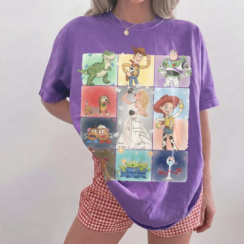 K&ouml;nnte beinhalten: Ein violettes Kurzarm-T-Shirt mit einem Raster aus Toy Story-Charakterillustrationen, darunter Woody, Buzz Lightyear, Rex, Slinky Dog, Mr. und Mrs. Potato Head, Jessie, die Aliens, Forky und eine blonde S&auml;ngerin in der Mitte.