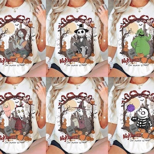 May include: A white t-shirt featuring a graphic print of various characters from The Nightmare Before Christmas, including Sally, Jack Skellington, and Oogie Boogie, framed by a dark tree design with pumpkins and the text Nightmare On Main Street.