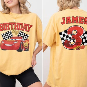 Op de afbeelding: Mosterdgeel T-shirt met een rode raceauto-afbeelding en de tekst "BIRTHDAY Boy". De achterkant van het shirt toont de naam "JAMES", het nummer "3" en geblokte vlaggen.