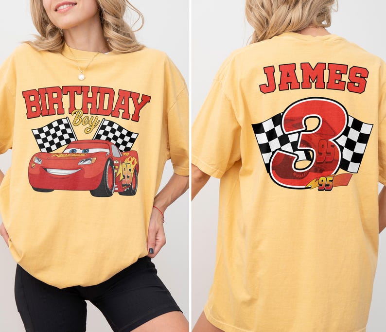 Op de afbeelding: Mosterdgeel T-shirt met een rode raceauto-afbeelding en de tekst "BIRTHDAY Boy". De achterkant van het shirt toont de naam "JAMES", het nummer "3" en geblokte vlaggen.