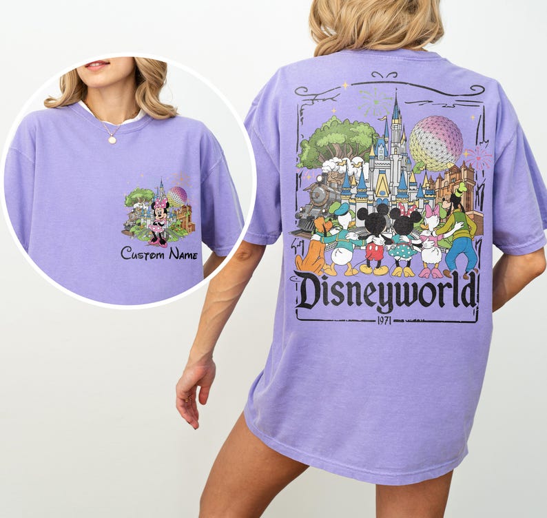 May include: A lilac-colored t-shirt featuring a Disney theme. The front has a Minnie Mouse graphic with the text "Custom Name". The back displays a colorful Disney World graphic with the text "Disneyworld" and the year "1971".