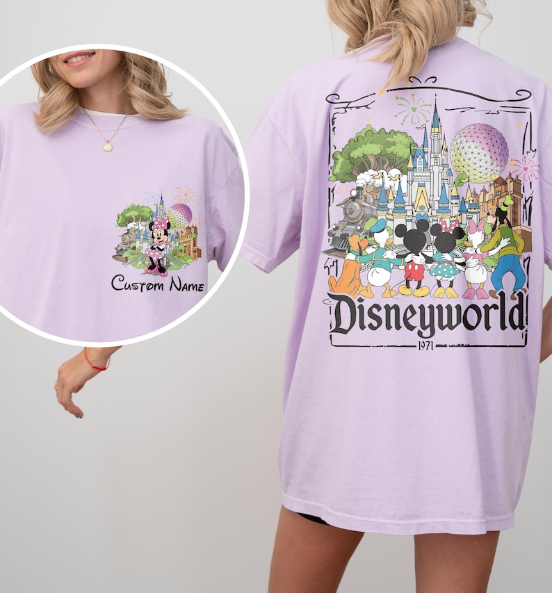 May include: A light purple t-shirt featuring a front graphic of Minnie Mouse in front of a castle and fireworks, with the text "Custom Name". The back of the shirt has a large graphic of Disney characters and the text "Disneyworld 1971".