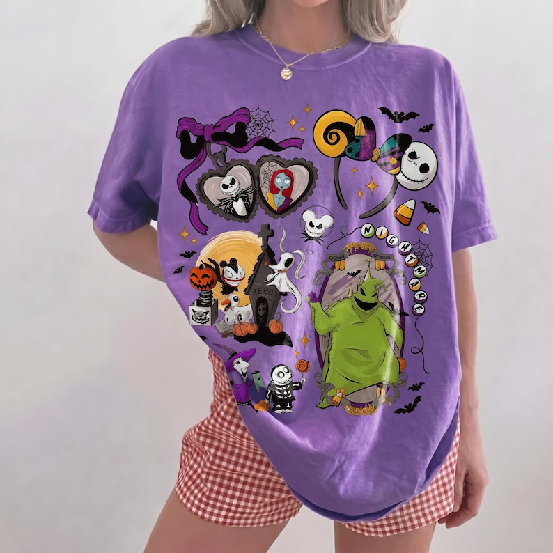 K&ouml;nnte beinhalten: Ein lila T-Shirt mit einem farbenfrohen Grafikdesign mit Charakteren und Elementen aus "The Nightmare Before Christmas". Das Design umfasst Jack Skellington, Sally, Oogie Boogie und andere Halloween-Motive.