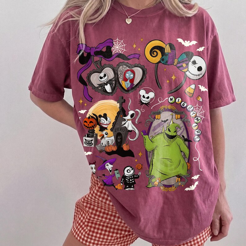 K&ouml;nnte beinhalten: Ein weinrotes T-Shirt mit einem Design mit Figuren aus "The Nightmare Before Christmas". Die Grafik zeigt Jack Skellington, Sally, Zero und Oogie Boogie sowie andere Halloween-Motive. Das Shirt hat einen Rundhalsausschnitt und kurze &Auml;rmel.